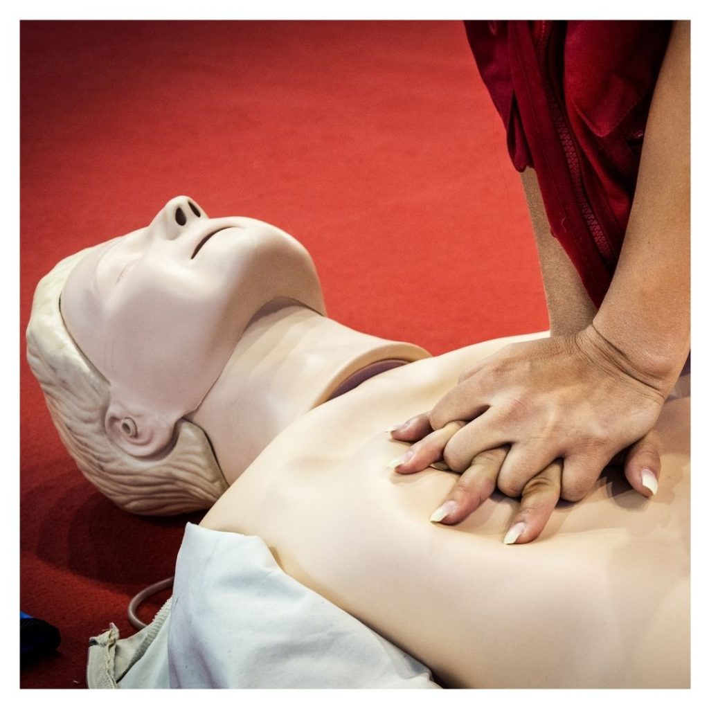 person practicing CPR on dummy